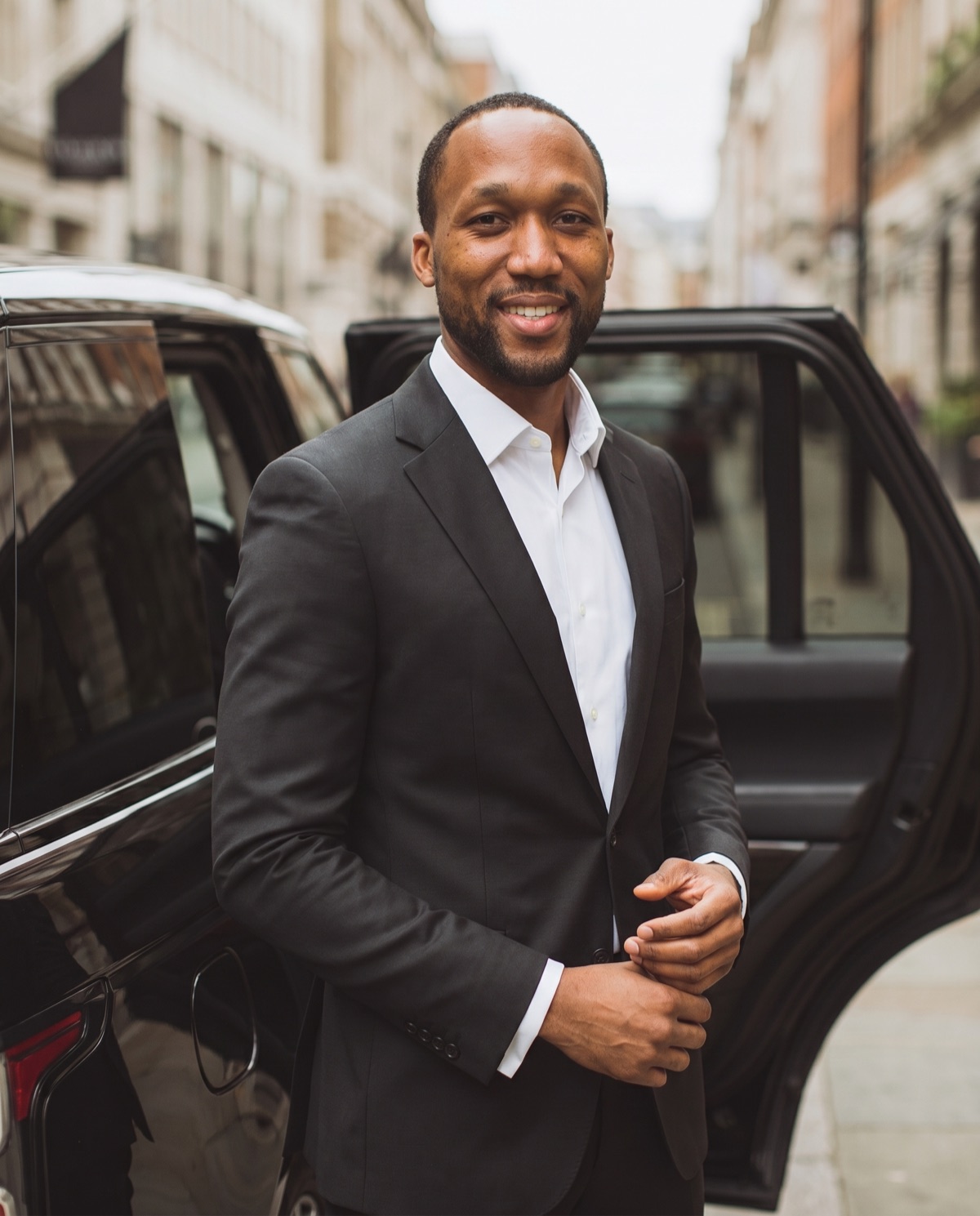 Oudane, founder of Your Transporter, standing beside a luxury sedan